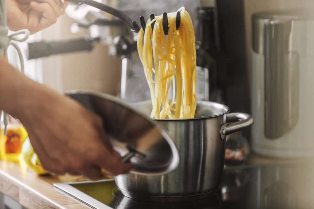 Hjemmelavet pasta der trækkes op ad en gryde.