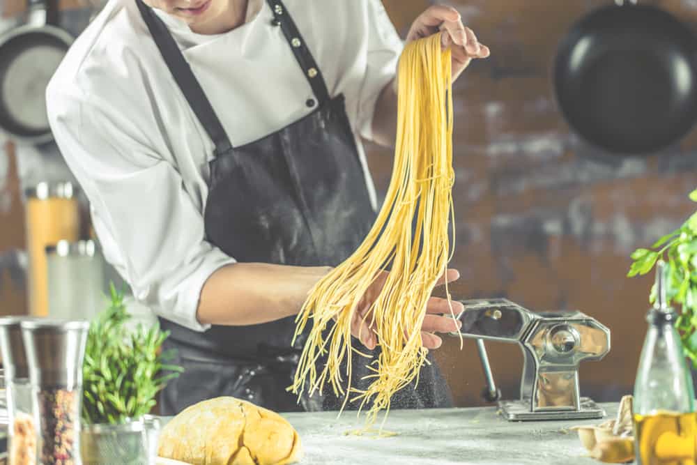 Mand med forklæde der laver hjemmelavet pasta.